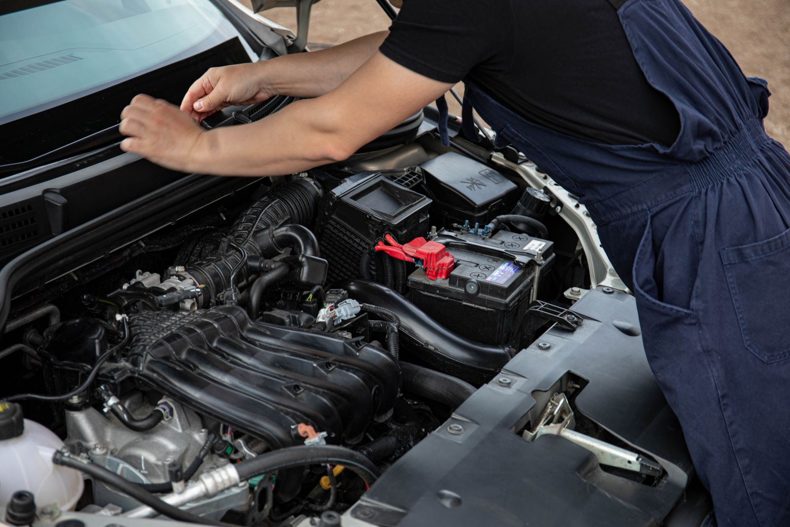 Mechanic working under the hood of a car outdoors